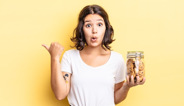 Joven hispana mirando asombrado con incredulidad. concepto de botella de galletas