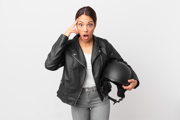 Joven hispana mirando sorprendido, dándose cuenta de un nuevo pensamiento, idea o concepto. concepto de piloto de moto