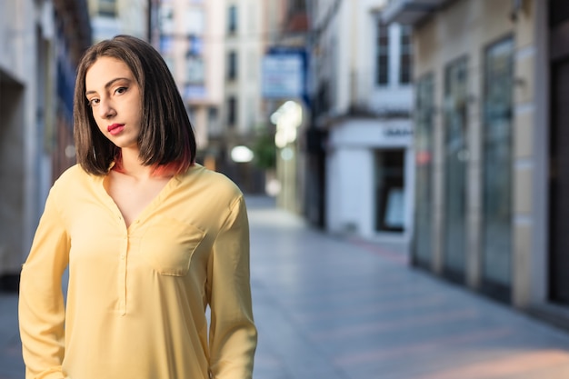 Joven hispana mujer independiente y segura en una calle urbana de Toledo España estilo de vida streetwear retrato de color amarillo del año con estilo