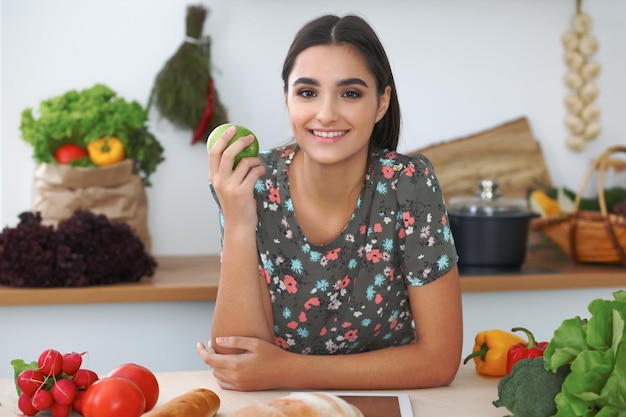 Joven hispana o estudiante cocinando en la cocina Chica usando tableta para hacer compras en línea o encontrar una nueva receta