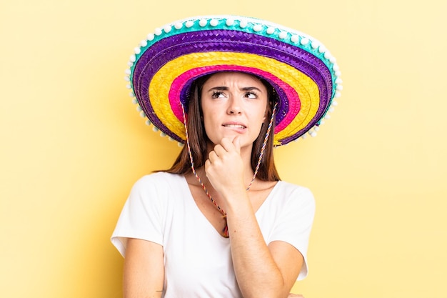 Joven hispana pensando sintiéndose dudoso y confundido concepto de sombrero mexicano