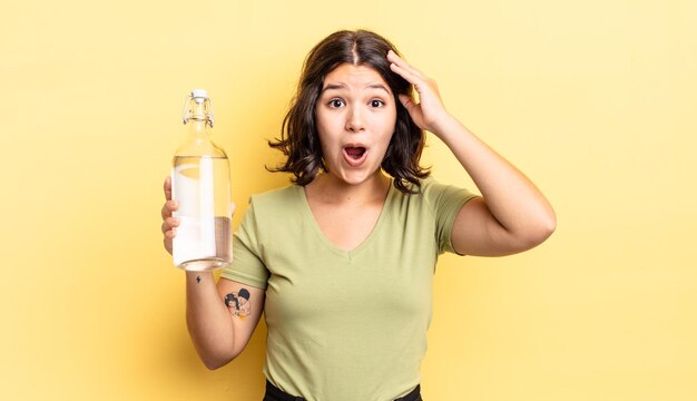 Joven hispana que parece feliz, asombrada y sorprendida. concepto de botella de agua