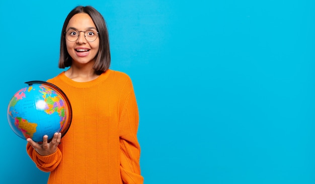 Foto joven hispana que parece feliz y gratamente sorprendida, emocionada con una expresión fascinada y conmocionada