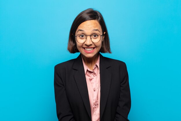 Joven hispana que parece feliz y tonta con una sonrisa amplia, divertida y chiflada y los ojos bien abiertos