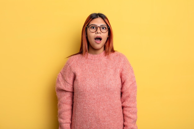 Joven hispana que parece muy sorprendida o sorprendida, mirando con la boca abierta diciendo wow