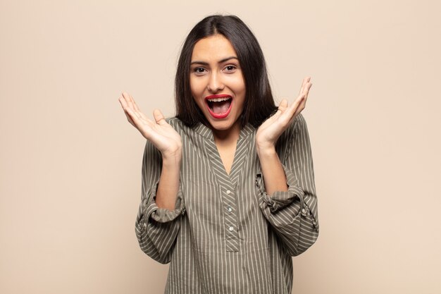 Joven hispana que se siente conmocionada y emocionada, riendo, asombrada y feliz por una sorpresa inesperada