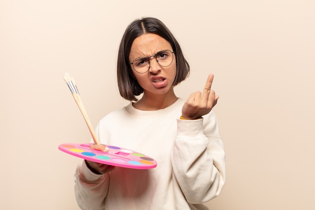 Foto joven hispana que se siente enojada, molesta, rebelde y agresiva, moviendo el dedo medio, contraatacando