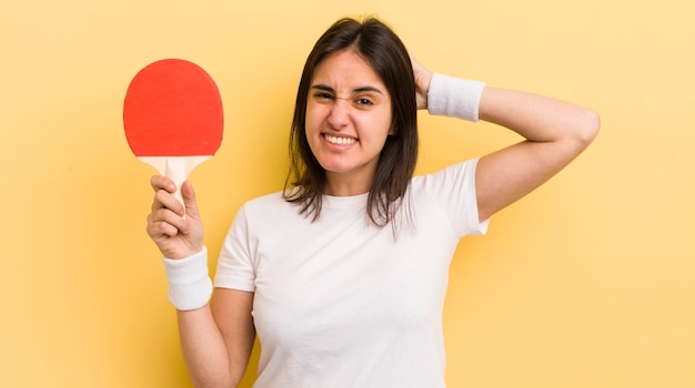 Joven hispana que se siente estresada ansiosa o asustada con las manos en la cabeza concepto de ping pong