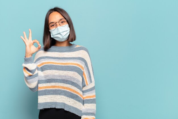 Joven hispana que se siente feliz, relajada y satisfecha, mostrando aprobación con gesto bien, sonriendo