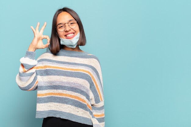 Foto joven hispana que se siente feliz, relajada y satisfecha, mostrando aprobación con gesto bien, sonriendo