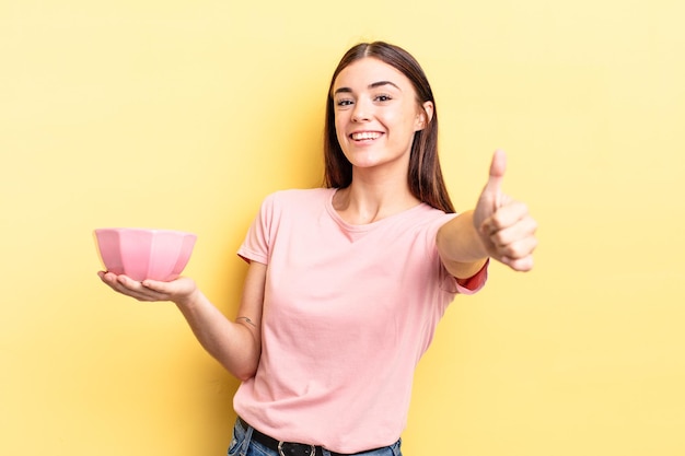 Joven hispana que se siente orgullosa, sonriendo positivamente con los pulgares hacia arriba. concepto de cuenco vacío