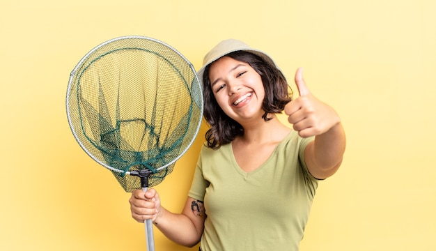 Joven hispana que se siente orgullosa, sonriendo positivamente con los pulgares hacia arriba. concepto de red de pescadores