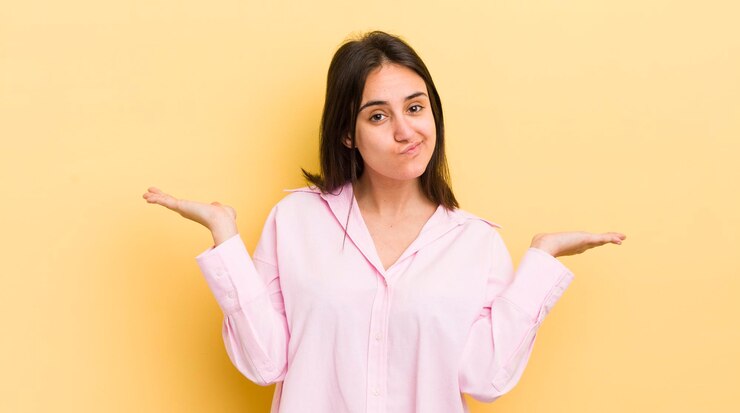 Foto joven hispana que se siente perpleja y confundida dudando de ponderar o eligiendo diferentes opciones con expresión graciosa