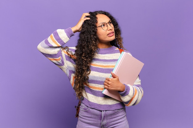 Foto joven hispana que se siente perpleja y confundida, rascándose la cabeza y mirando hacia un lado. concepto de estudiante