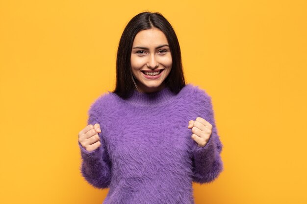 Joven hispana que se siente sorprendida, emocionada y feliz, riendo y celebrando el éxito, diciendo ¡guau!