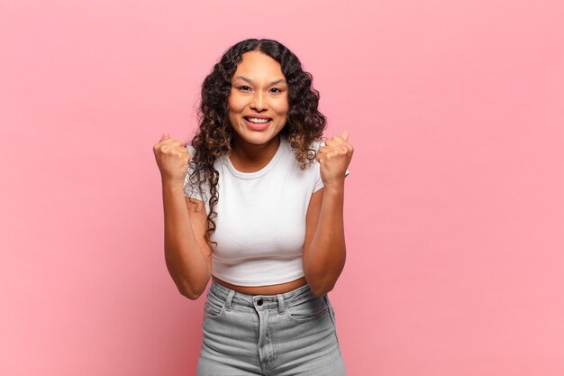 Joven hispana que se siente sorprendida, emocionada y feliz, riendo y celebrando el éxito, diciendo ¡guau!