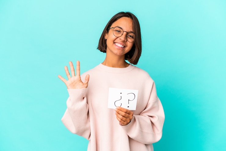Foto joven hispana de raza mixta sosteniendo un tablero de interrogatorio sonriendo