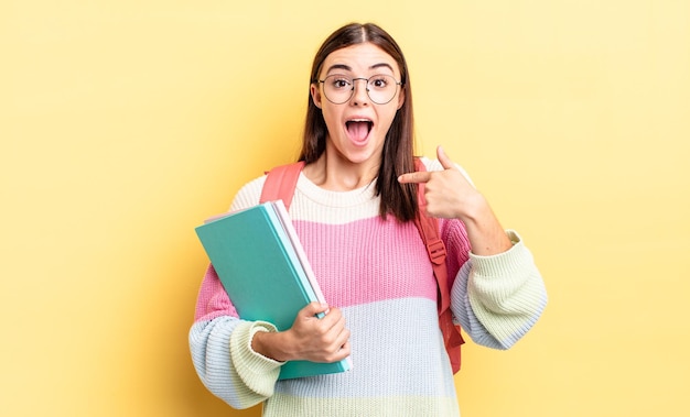 Joven hispana sintiéndose feliz y apuntando a sí misma con un emocionado. concepto de estudiante