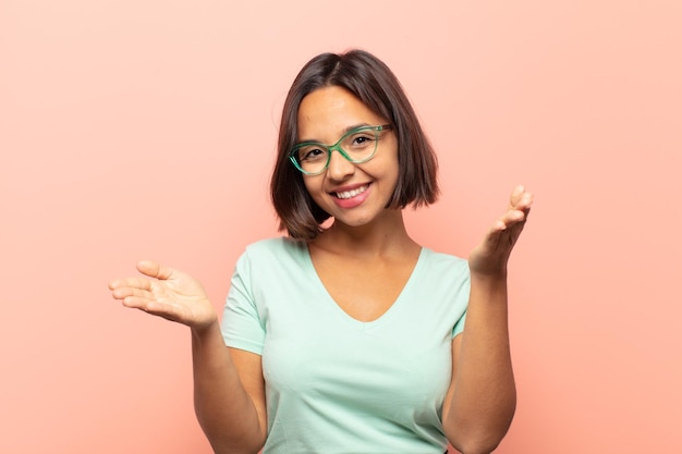 Joven hispana sonriendo alegremente dando un cálido, amistoso y amoroso abrazo de bienvenida, sintiéndose feliz y adorable