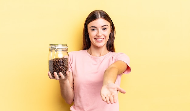 Joven hispana sonriendo felizmente con amable y ofreciendo y mostrando un concepto. concepto de granos de cafe