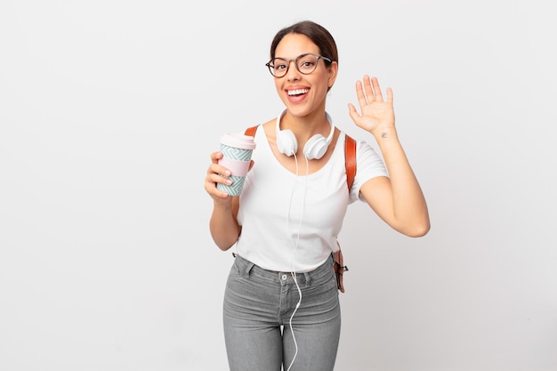 Joven hispana sonriendo felizmente, saludando con la mano, dándote la bienvenida y saludándote. concepto de estudiante