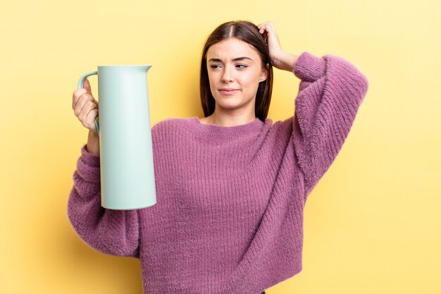 joven hispana sonriendo felizmente y soñando despierto o dudando. concepto de termo de café