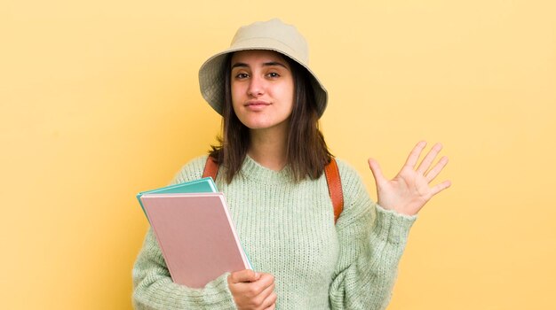 Joven hispana sonriendo y luciendo amigable mostrando el concepto de estudiante número cinco