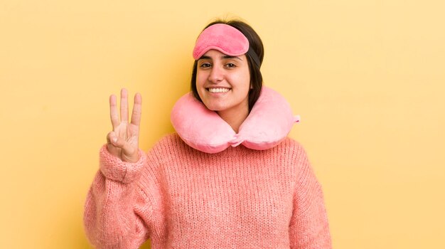 Joven hispana sonriendo y luciendo amigable mostrando el concepto de pasajero de vuelo número tres