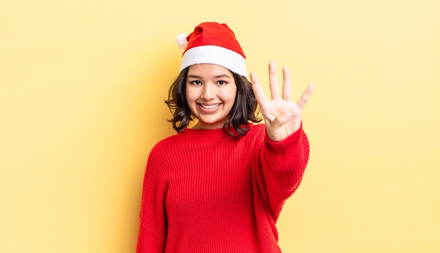 Joven hispana sonriendo y mirando amigable, mostrando el número cuatro. concepto de navidad