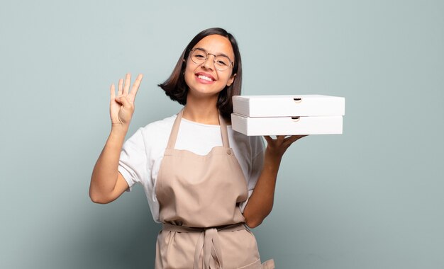 Joven hispana sonriendo y mirando amistosamente, mostrando el número cuatro o cuarto con la mano hacia adelante, contando hacia atrás