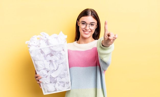 Foto joven hispana sonriendo con orgullo y confianza haciendo el número uno. concepto de basura de falla