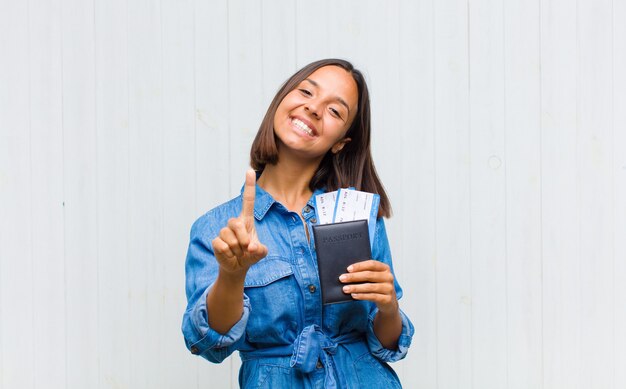 Joven hispana sonriendo con orgullo y confianza haciendo la pose número uno triunfalmente, sintiéndose como un líder