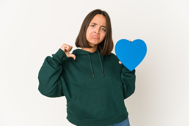 Joven hispana sosteniendo una forma de corazón se siente orgullosa y segura de sí misma, ejemplo a seguir.