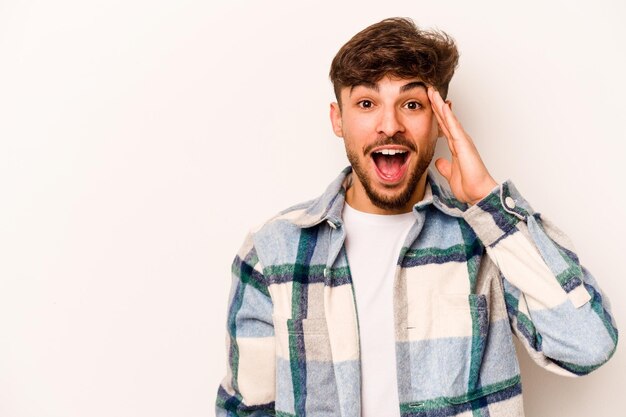 Foto joven hispano aislado de fondo blanco grita fuerte mantiene los ojos abiertos y las manos tensas