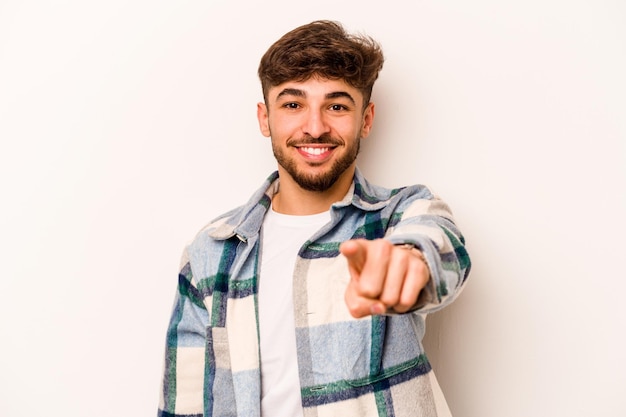 Joven hispano aislado sobre fondo blanco sonrisas alegres apuntando al frente