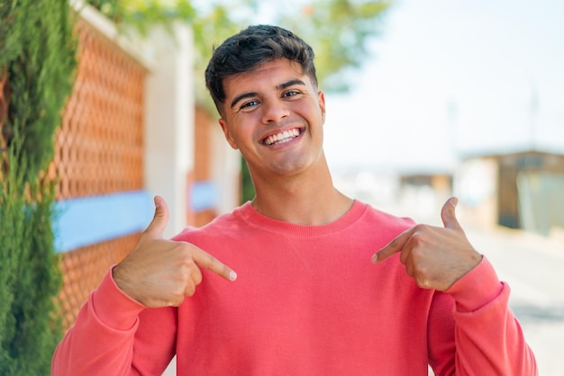 Foto joven hispano al aire libre orgulloso y satisfecho de sí mismo