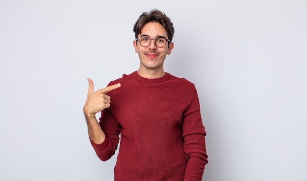 Joven hispano apuesto que se ve orgulloso, confiado y feliz, sonriendo y apuntándose a sí mismo o haciendo el signo número uno