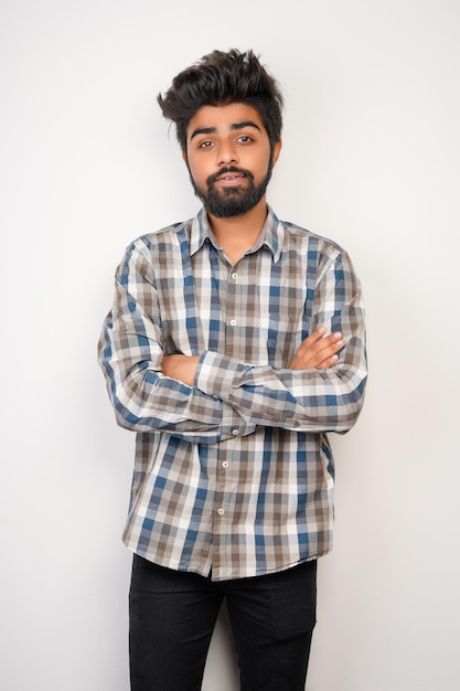 Joven hispano barbudo con camisa a cuadros sobre fondo blanco con expresión positiva tiene una amplia sonrisa interesada Mire allí por favor buscando algo o encontró algo