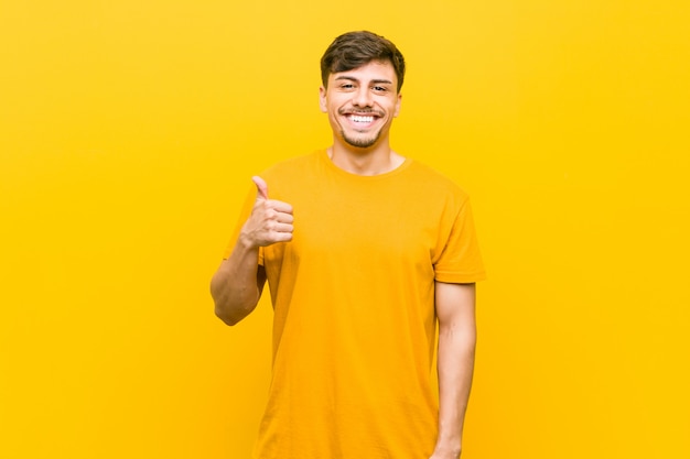 Joven hispano casual sonriendo y levantando el pulgar hacia arriba