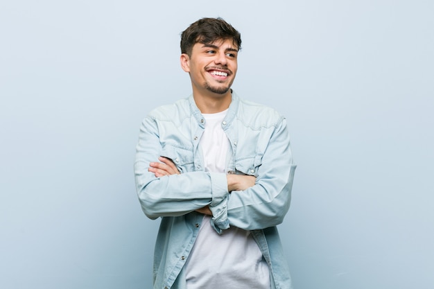 Joven hispano cool hombre sonriente confiado con los brazos cruzados.