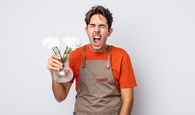 joven hispano gritando agresivamente, luciendo muy enojado. concepto de floristería