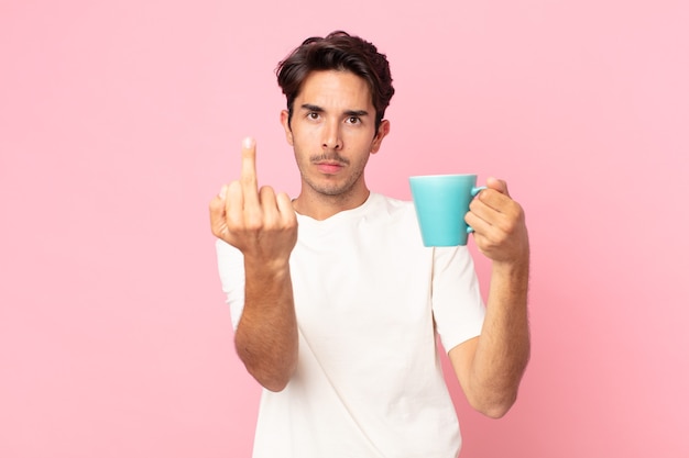 Joven hispano que se siente enojado, molesto, rebelde y agresivo y sosteniendo una taza de café