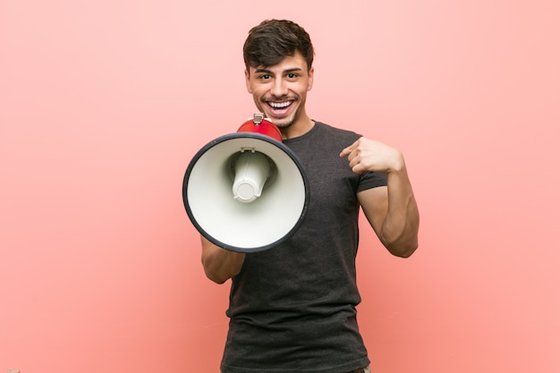 Foto el joven hispano que sostenía un megáfono sorprendió apuntándose a sí mismo, sonriendo ampliamente.