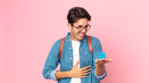 Joven hispano riendo a carcajadas de una broma hilarante con un juego de desafío de inteligencia