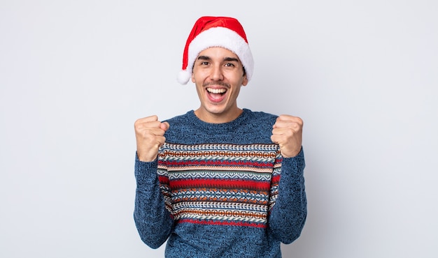 Joven hispano se siente conmocionado, riendo y celebrando el éxito. concepto de navidad y año nuevo