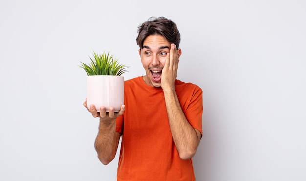 Joven hispano sintiéndose feliz, emocionado y sorprendido. concepto de planta decorativa