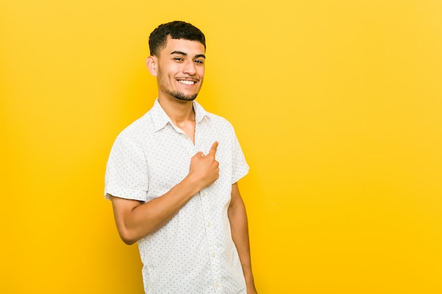 Joven hispano sonriendo y apuntando a un lado