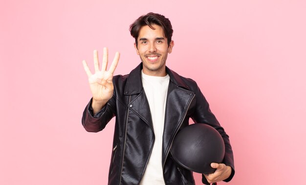 Joven hispano sonriendo y mirando amigable, mostrando el número cuatro. concepto de piloto de moto