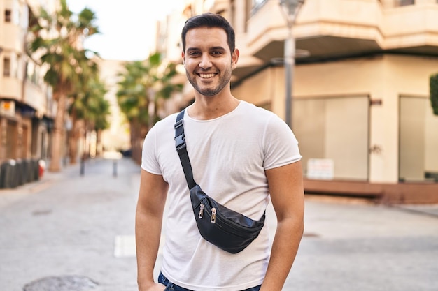 Joven hispano sonriendo seguro de pie en la calle