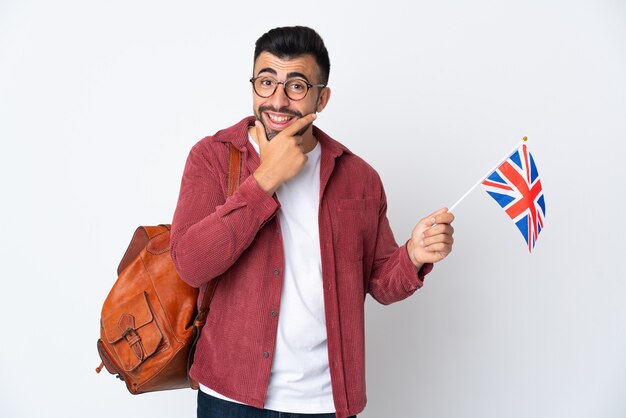 Joven hispano sosteniendo una bandera del Reino Unido feliz y sonriente